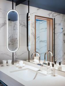 a bathroom with a sink and two mirrors at AMERON Zürich Bellerive au Lac in Zürich