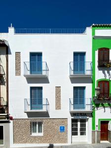 um edifício branco com janelas azuis e varandas em Nerja Casual Rooms em Nerja