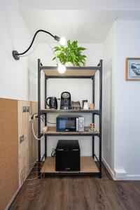 a room with a shelf with a microwave and a lamp at Hotel Gascogne in Toulouse