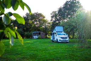 ein weißer Van auf einem Grasfeld geparkt in der Unterkunft camping chez l'habitant in Noyal-Muzillac