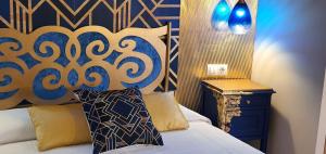 a bedroom with a bed with a blue and gold headboard at Hosteria Villa de Castro in Castro-Urdiales