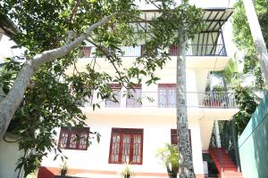 a white building with red windows and a balcony at Sumudu Villa in Hikkaduwa