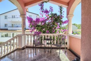 un balcón con 2 sillas y flores púrpuras en Hotel Villa Vera, en Fažana