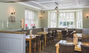 a restaurant with wooden tables and chairs and windows at The Valley Hotel, Anglesey in Valley