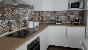 a kitchen with white cabinets and a microwave at A Casinha in Angra do Heroísmo