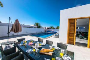 a patio with a table and chairs and a swimming pool at Villa Rossa - Villas Now - LH215 By Villas Now Ltd in Playa Blanca