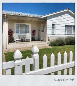 a white picket fence in front of a house at Melkbos Holiday Accommodation in Melkbosstrand