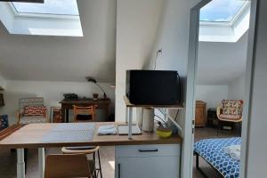 Habitación con escritorio, TV y dormitorio. en Vol de nuit - balade urbaine au centre d'Epernay, en Épernay
