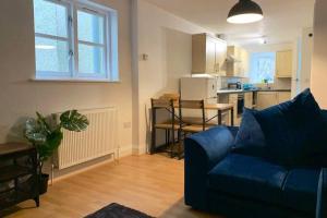 a living room with a blue couch and a kitchen at Biskey Howe Central - FREE off-site Health Club access with Pool, Sauna, Steam Room & Gym in Bowness-on-Windermere
