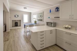 a kitchen with white cabinets and a counter top at Melkbos Holiday Accommodation in Melkbosstrand