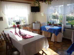 a dining room with two tables and chairs and windows at Pension Döser Strand in Cuxhaven
