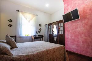 um quarto com uma cama e uma televisão na parede em Refúgio Pasárgada Guest House em Mairiporã