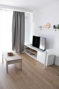 a white living room with a tv and a table at Superb seaview apartment in Playa de Las Americas in Playa de las Americas
