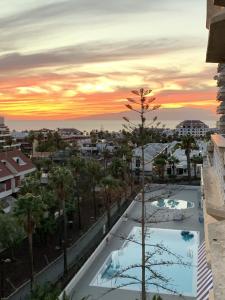 a view of the pool at sunset from the balcony of a hotel at Superb seaview apartment in Playa de Las Americas in Playa de las Americas