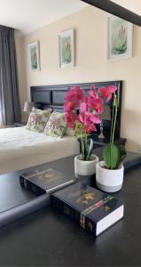 een slaapkamer met twee boeken en bloemen op een tafel bij Green Haven Luxury Apartments in Ezulwini
