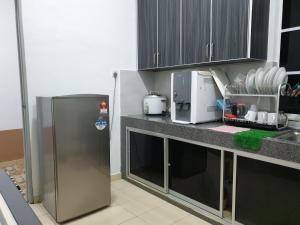a kitchen with a stainless steel refrigerator and cabinets at Inapdesa Teratak Bonda, Sepri REMBAU in Rembau