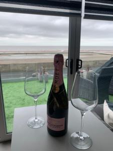 a bottle of wine and two glasses on a table at Beach View Apartment with balcony and sea view - pet friendly in Cleveleys
