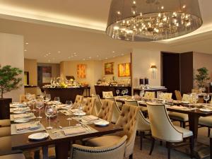 a dining room with tables and chairs and a chandelier at Joy Nostalg Hotel and Suites Manila Managed by The Ascott Limited in Manila