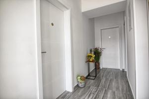 a hallway with white walls and wood floors and a door at Rooms DRAGICA in Pakoštane