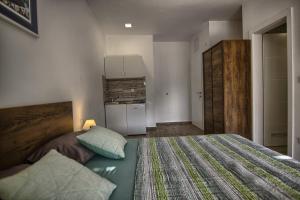 a bedroom with a large bed and a kitchen at Rooms DRAGICA in Pakoštane