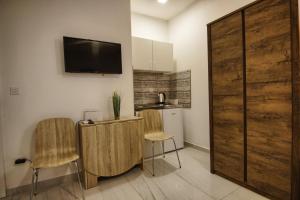 a kitchen with two chairs and a table with a tv on the wall at Rooms DRAGICA in Pakoštane +15 photos