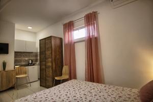 a bedroom with a bed and a window and a kitchen at Rooms DRAGICA in Pakoštane