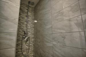 a shower in a bathroom with a stone wall at Rooms DRAGICA in Pakoštane