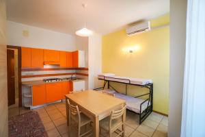 ビビオーネにあるCondominio Zodiacoのキッチン(オレンジ色のキャビネット、テーブル、テーブル、椅子付)