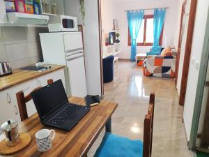 Near Airport Comfy Stay Gran Canaria في Playa del Burrero: جهاز كمبيوتر محمول يجلس على طاولة خشبية في مطبخ