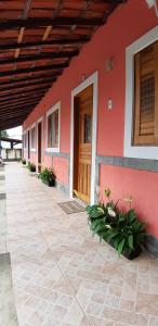 un edificio rojo con una puerta de madera y flores en Patricio's Chalés Ilhabela, en Ilhabela