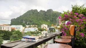 a table with books and chairs on a balcony with a mountain at Draha Halong Hotel in Ha Long