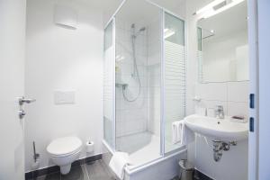 y baño con ducha, aseo y lavamanos. en Alpenglühen Smart Hotel, en Olching