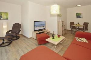 a living room with red furniture and a flat screen tv at Der Landhof Schwalbennest LH-204 in Stolpe auf Usedom