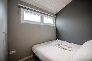 a small bedroom with a bed with a window at BUDDHA BEACH BUNGALOWS Adults Only in Zandvoort