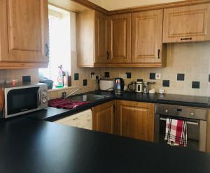 a kitchen with wooden cabinets and a black counter top at Letterkenny Town Centre Apartment in Letterkenny