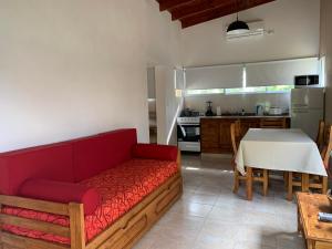 a living room with a red couch and a kitchen at Complejo La Querencia de Colón in Colón