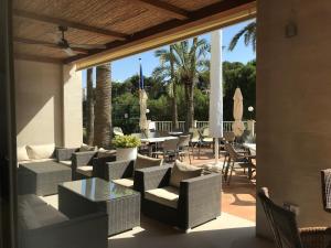 un patio con sillas de mimbre y mesas. en Hotel Apartamentos Cala Santanyi, en Cala Santanyi