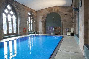 a large swimming pool with blue water in a building at The Ness Apartment Highland Club Scotland in Fort Augustus