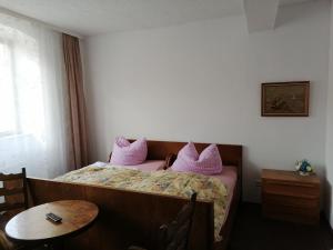 a bedroom with a bed with pink pillows and a table at Gasthaus Zur Rose in Malsch