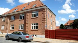 une voiture en argent garée devant un bâtiment en briques dans l'établissement Billesgade Rooms, à Odense