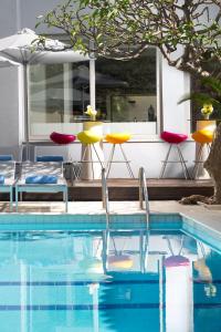 een zwembad met stoelen, een tafel en een parasol bij AQUAMARE CITY and BEACH in Rhodos-stad