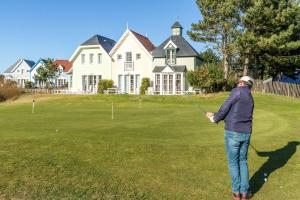 a man is playing golf in front of a house at Belle Dune in Fort-Mahon-Plage