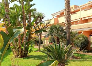 un jardín con palmeras y plantas frente a un edificio en Vera Sol y Mar - Naturist Zone, en Playas de Vera