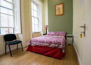 a room with a bed, chair, table and window at The Apache Hostel in Dublin