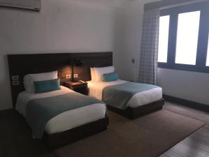 a hotel room with two beds and a window at Sophia Hotel in Cartagena de Indias