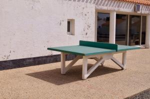 a green bench sitting in front of a building at Petite maison reposante pour 2 au bord de mer in Brétignolles-sur-Mer