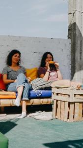 two women sitting on a bench looking at their cell phones at Nanasqa Hostel en Nasca / Nazca in Nazca