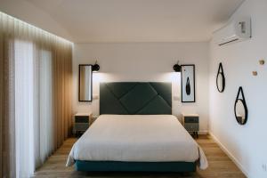 een slaapkamer met een groot wit bed en 2 lampen bij Villa Teresa apartamentos in Vila Nova de Gaia
