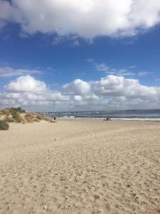 een zandstrand met mensen in het water en de wolken bij Alojamiento PISCIS in Puerto Madryn