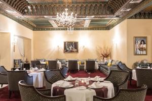 a dining room with tables and chairs and a chandelier at Savoy Le Grand Hotel Marrakech in Marrakech
